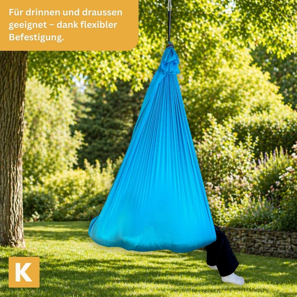 Kind entspannt draussen in hellblauer Kiddyflow Therapieschaukel  – aufgehängt an einem Baum.