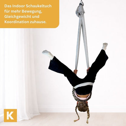 Kind schaukelt kopfüber in der Kiddyflow Therapieschaukel und bewegt sich aktiv im Innenraum.
