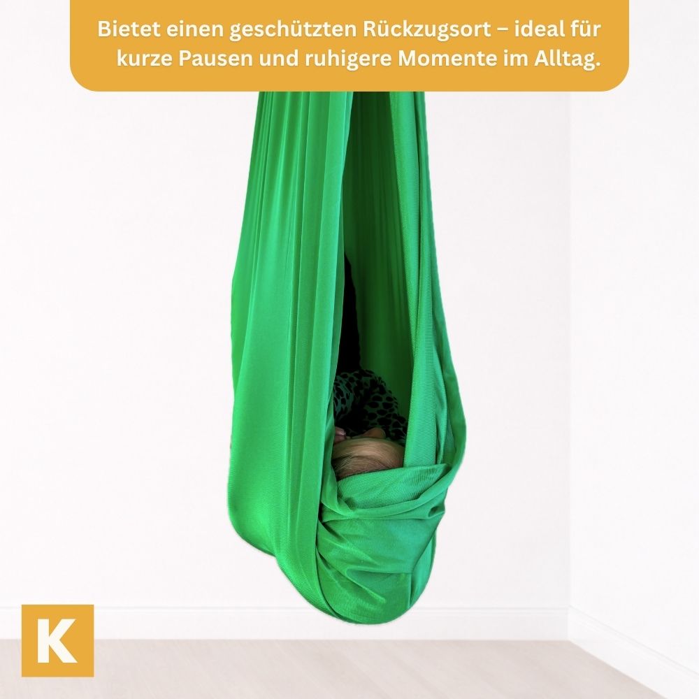 Kind geborgen in einer grünen Therapieschaukel von Kiddyflow im Innenbereich